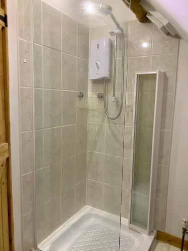 a shower with a glass door in a bathroom at Deri-Down Guest House in Abergavenny
