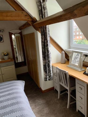 a bedroom with a desk and a bed and a window at Deri-Down Guest House in Abergavenny