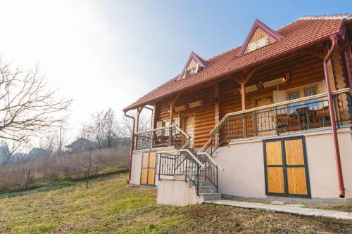 uma casa de madeira com uma varanda numa colina em Apartmani Žuti Leptir em Vrdnik