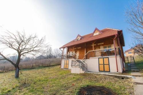 uma casa de madeira numa colina com uma árvore em Apartmani Žuti Leptir em Vrdnik