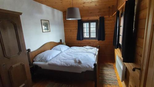 ゾンネンアルペ・ナスフェルトにあるOne-Of-A-Kind NASSFELD APARTMENTSの木造キャビン内のベッド1台が備わるベッドルーム1室を利用します。