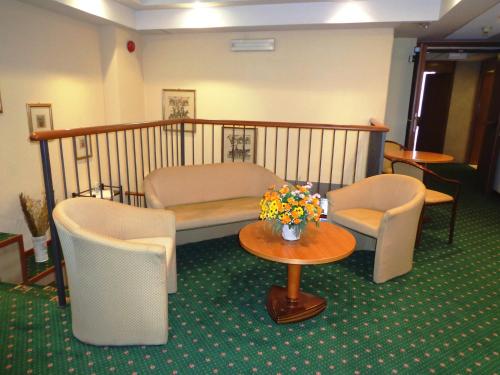 a room with a bed and chairs and a table with flowers at Hotel Select in Montecchio Emilia