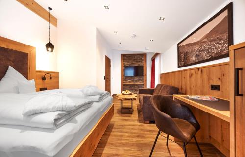 a bedroom with a bed and a desk and chairs at Wellness- und Bierhotel Adam Bräu in Bodenmais