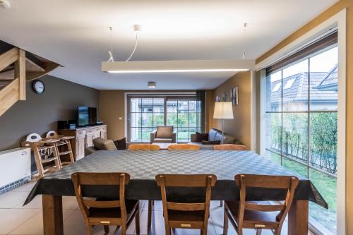 a dining room and living room with a table and chairs at Vakantiehuisje Walhofpark 10 in De Panne