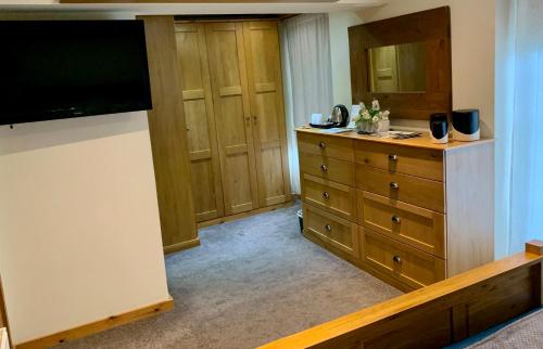 a bedroom with a dresser and a large television at Deri-Down Guest House in Abergavenny