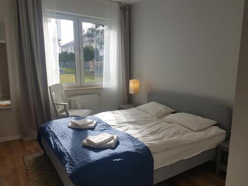 een slaapkamer met een bed met een blauwe deken en een raam bij Apartament Jasińskiego z ogrodem in Piaseczno