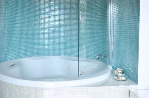 a bathroom with a tub with blue tiles at Belleview Villa in Barcelona