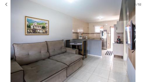 a living room with a couch and a kitchen at Casa com piscina, wifi e churrasqueira em unamar. in Tamoios