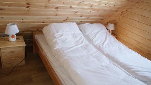 a bed in a room with a wooden wall at Wantaris - domki letniskowe z ogródkiem Mielno-Mielenko in Mielno