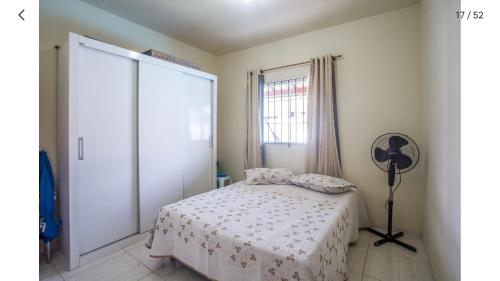 a bedroom with a bed and a fan and a window at Casa com piscina, wifi e churrasqueira em unamar. in Tamoios