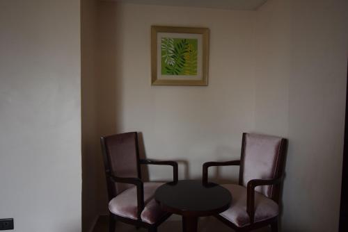 two chairs and a table with a picture on the wall at Noble House Hotel in Kumasi