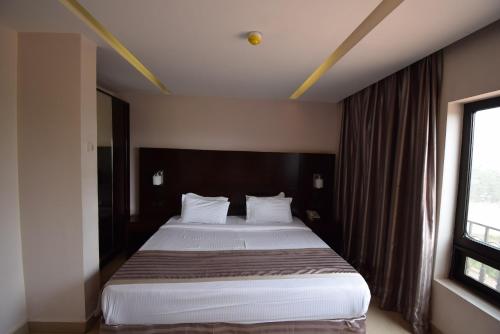 a bedroom with a large bed with a large window at Noble House Hotel in Kumasi
