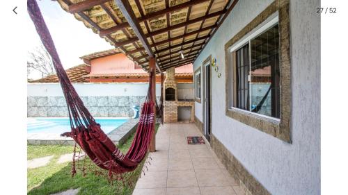 a room with hammocks outside of a house at Casa com piscina, wifi e churrasqueira em unamar. in Tamoios