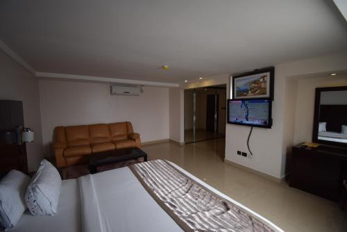 a living room with a couch and a flat screen tv at Noble House Hotel in Kumasi
