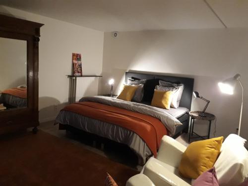 ein Schlafzimmer mit einem Bett mit gelben Kissen und einem Sofa in der Unterkunft Vakantiewoning BC Bed en Comfort in Bilzen