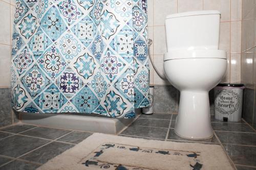 a bathroom with a toilet and a blue and white shower curtain at Bella Vita Style rooms & apartments in Pitsidia