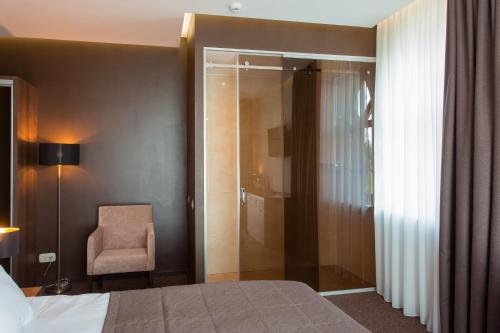 a hotel room with a bed and a chair and a shower at WISH Aqua&SPA Resort in Vishenki