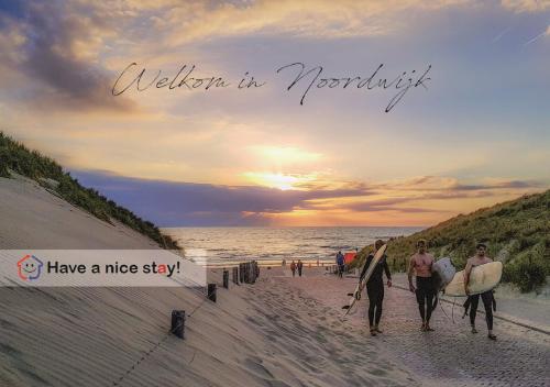 a group of people walking on the beach with surfboards at Have a nice stay! - Le Souterrain in Noordwijk aan Zee