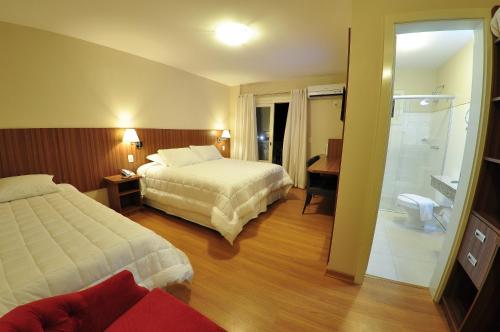 a hotel room with two beds and a bathroom at Rothenburg Hotel in Nova Petrópolis
