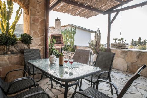 a table and chairs on a patio with wine glasses at Bella Vita Style rooms & apartments in Pitsidia