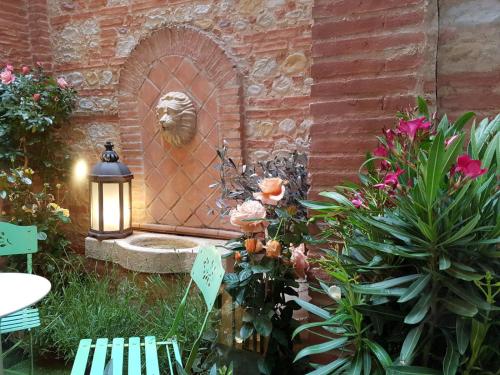 a garden with a brick wall with a fountain at Hôtel des Arts in Toulouse
