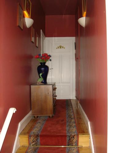a hallway with a vase of flowers on a table at L OUSTALOU MAISON D HOTES DE CHARME EN AUVERGNE PISCINE PRIVEE CHAUFFéE in Saint-Nectaire
