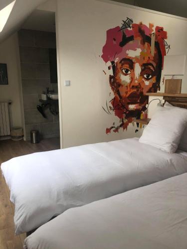 a bedroom with a white bed with a painting on the wall at Ginkgo Maison d'hôtes in Amiens