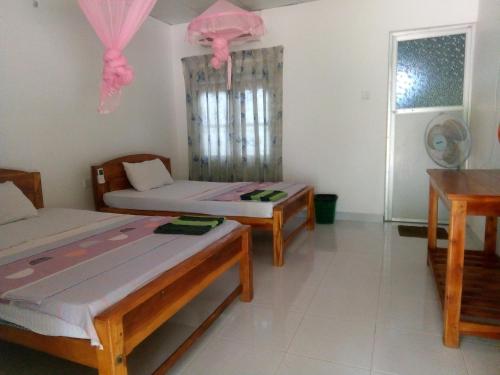 Zimmer mit 2 Betten, 2 Tischen und einem Fenster in der Unterkunft Hotel Sea Shadow in Trincomalee