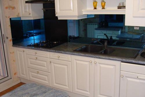 une cuisine avec des armoires blanches et un évier dans l'établissement T4 proche Hypercentre, box auto privé et loggia, à Toulouse