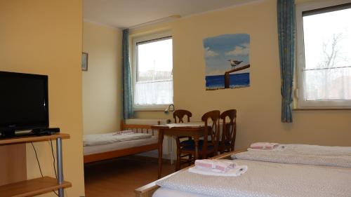 a room with two beds and a table and a tv at Logia Hotel garni in Neuharlingersiel