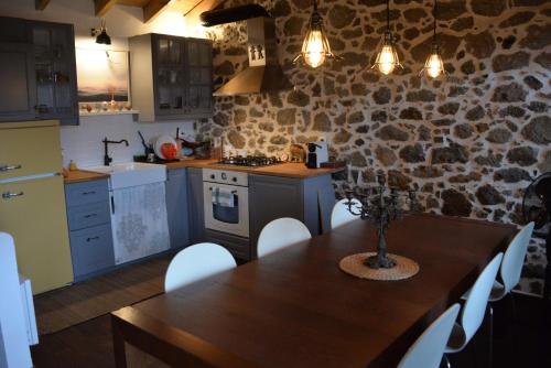 a kitchen with a wooden table and a stone wall at The fig tree house in Samothráki