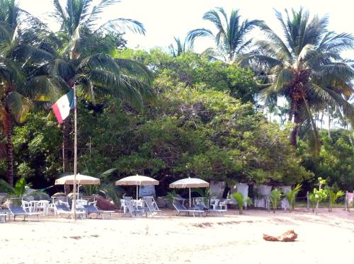 a beach with chairs and umbrellas and a flag at Junto al Rio Bungalows & Suites in Sayulita