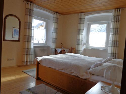 a bedroom with a bed and two windows at Ferienwohnungen Leo Werland-Ehses in Zeltingen-Rachtig