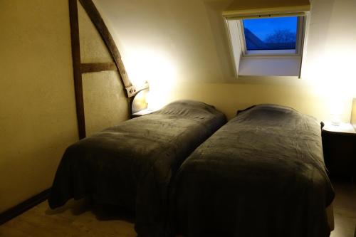 - 2 lits dans une petite chambre avec fenêtre dans l'établissement Gîte rural Les petites têtes, à Leuze-en-Hainaut