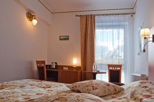 a bedroom with a bed and a desk and a window at Piastun SPA&Wellness Krynica-Zdrój in Krynica Zdrój