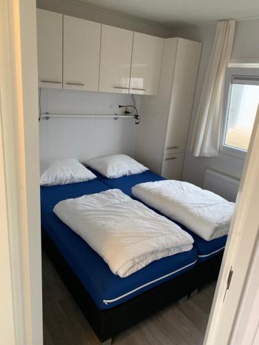 2 camas en una habitación pequeña con armarios blancos en Chalet Helmgras, en Beek