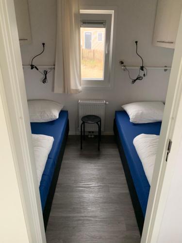 twee bedden in een kleine kamer met een raam bij Chalet Helmgras in Beek