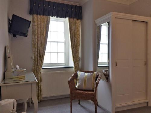 a room with a chair and a desk and two windows at Tregiffian Farm B&B in Penzance