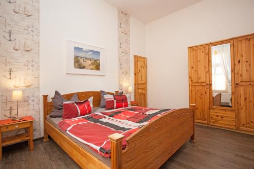 ein Schlafzimmer mit einem großen Holzbett mit roten Kissen in der Unterkunft Villa Atelier in Borkum