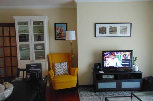 a living room with a tv and a yellow chair at Oporto East House in Porto