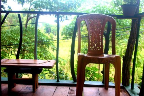 a pair of chairs sitting on a porch with a window at Angry Birds Tree house in Habarana