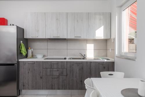 a kitchen with wooden cabinets and a stainless steel refrigerator at Apartment Tonka in Barbat na Rabu