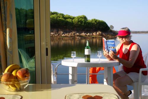 a woman sitting at a table reading a book at Amieira Marina in Amieira