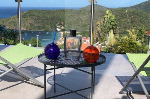 a table with two colorful vases on top of a balcony at Le DAMOUR Appartement 1 ou 2 chambres in Les Anses-dʼArlets