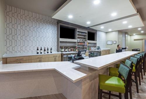 a bar with green chairs and a woman standing at a counter at Holiday Inn - Amarillo East by IHG in Amarillo