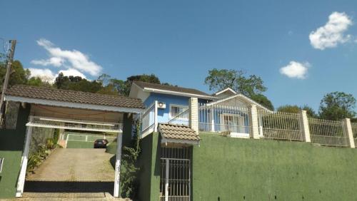 una casa con una valla verde y un camino de entrada en Lago do Bosque, en Gramado