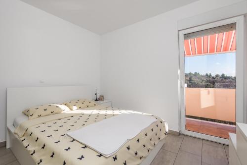 a white bedroom with a bed and a large window at Apartment Tonka in Barbat na Rabu