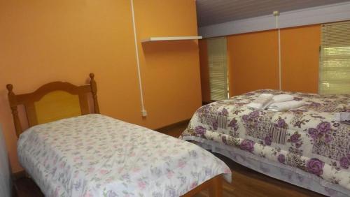 2 camas en un dormitorio con paredes amarillas en Lago do Bosque, en Gramado