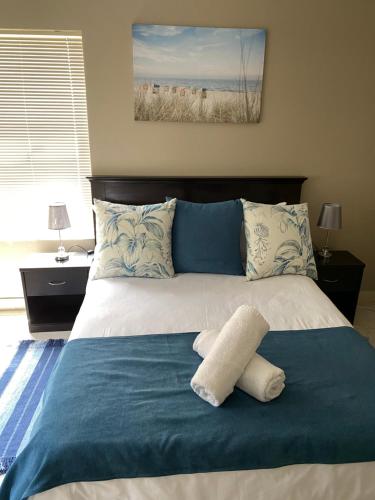 ein Bett mit einer blauen Decke und Kissen darauf in der Unterkunft Sunset Heights in Langebaan