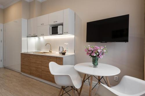 a kitchen with a white table and a vase of flowers at Apartamenty w Klaudynie in Klaudyn